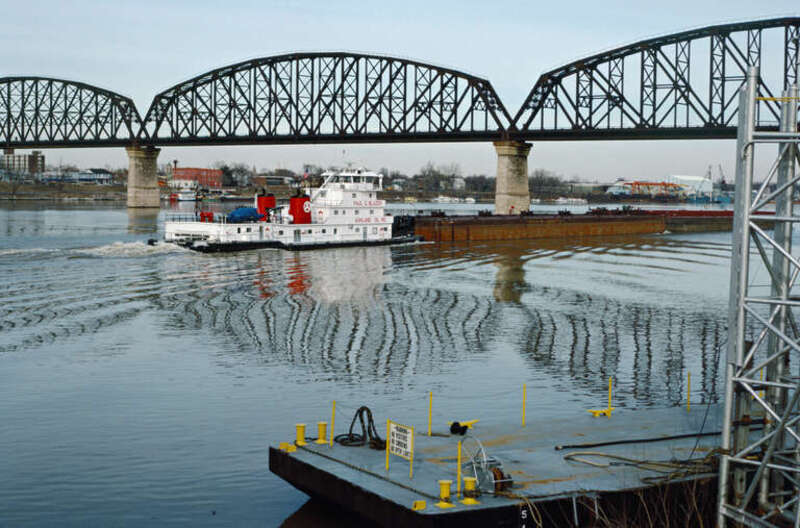 Looking NNE from Ashland asphalt terminal just above JFK Bridge.
Black barge with gray deck is permanently moored next to pylons.
Towboat &quot;Paul G. Blazer&quot; (doc. # 918951) upbound at Big Four Bridge.
.
&quot;Paul G. Blazer&quot; (150x45, twin Cat 3606 diesels,