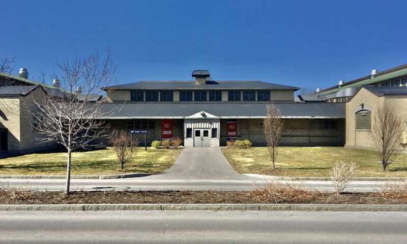 As seen in March 2021, the main façade of the Cattle Building on the New York State Fairgrounds, as seen from the back end of the Science &amp;amp; Industry Building. Eschewing the High Neoclassical style employed by the Buffalo firm of Green &amp;amp; Wicks