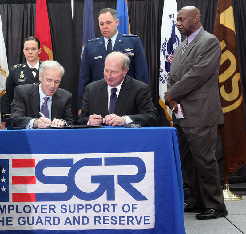 SANDY SPRINGS, Feb. 13, 2013  - Major Gen. Jim Butterworth (center standing), Georgia's Adjutant General, along with UPS employees who serve in the Guard and Reserve, watch while Scott Davis (seated left), UPS chairman and CEO, and James Rebholz,