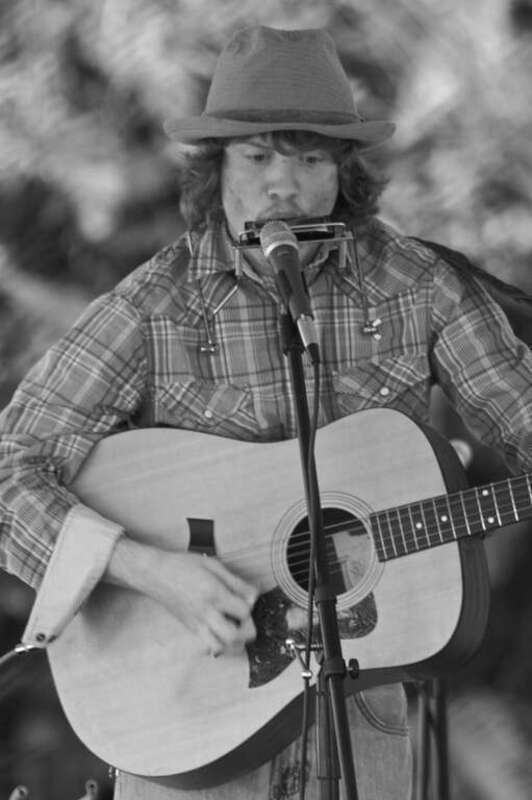 Man playing harmonica into microphone while strumming guitar. 7th annual Orlando Folk Festival, Lake Formosa, Florida; February 15, 2009.
