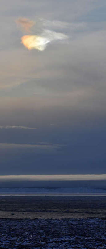 An iridescent cloud hovers above the icebergs in Cook Inlet. This might be an atmospheric phenomenon called a  &quot;sundog,&quot; but I'm not totally sure.

winterbear.com
