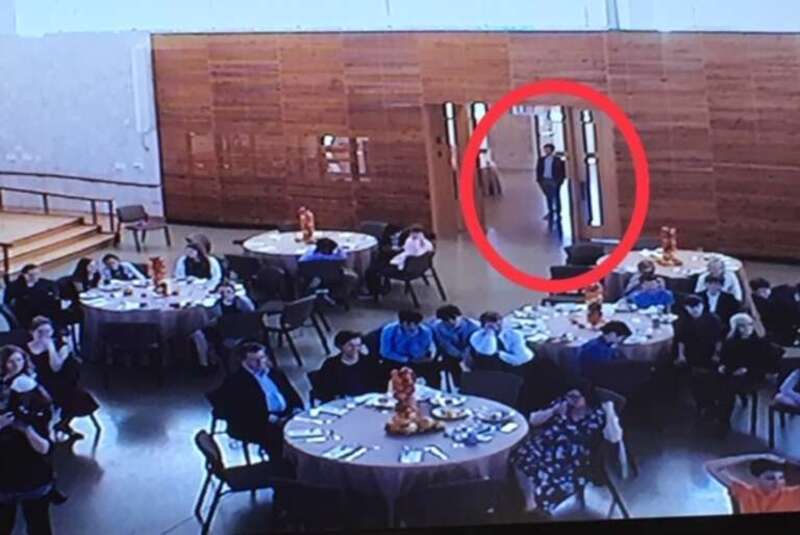 Man standing against wall in crowded room highlighted by red circle