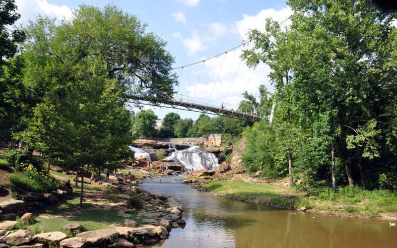 The Liberty Bridge, 345 ft long and 12 ft wide, is supported by a single suspension cable. It crosses the Reedy River in Falls Park.