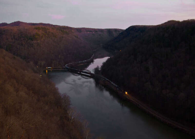 The sun has dipped below the horizon in this view from Hawk's Nest in Ansted, WV.  A CSX freight heads west after crossing the New River on a late November day.