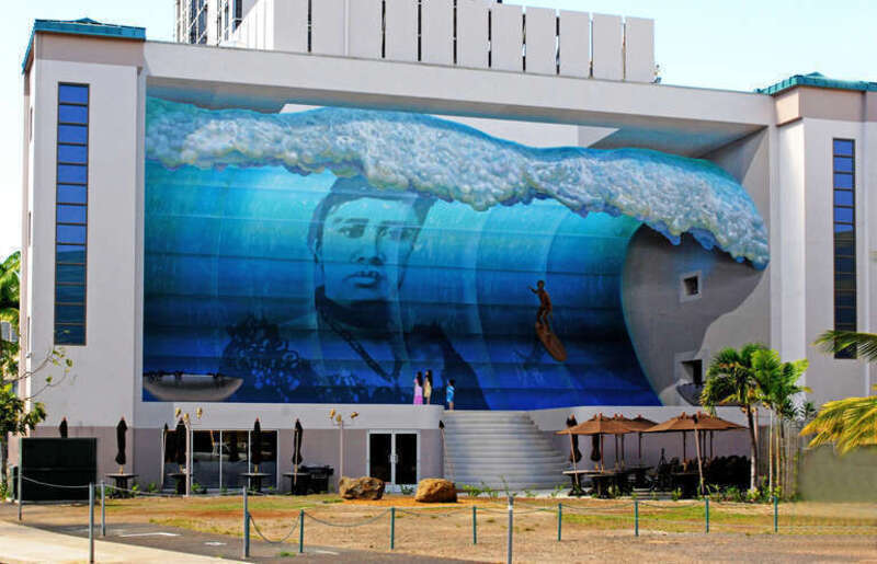 Larger than life, the epic wave behind surfer pioneer Duke Kahanamoku is Queen Lili’uokalani herself. Bold and defiant, she endures the tide of western conquests. This glass wave monument honors her spirit that still pounds in the hearts of her
