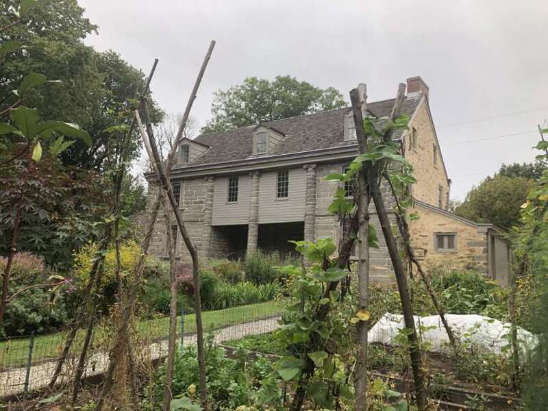 Rear view of John Bartram's stone house seen through colonial-inspired vegetable garden at historic Bartram's Garden in Philadelphia, PA.