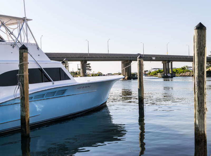 Rudee Inlet Bridge and boats at the Virginia Beach Fishing Center. The boat on the left is named &quot;GIT*R*DONE&quot;.