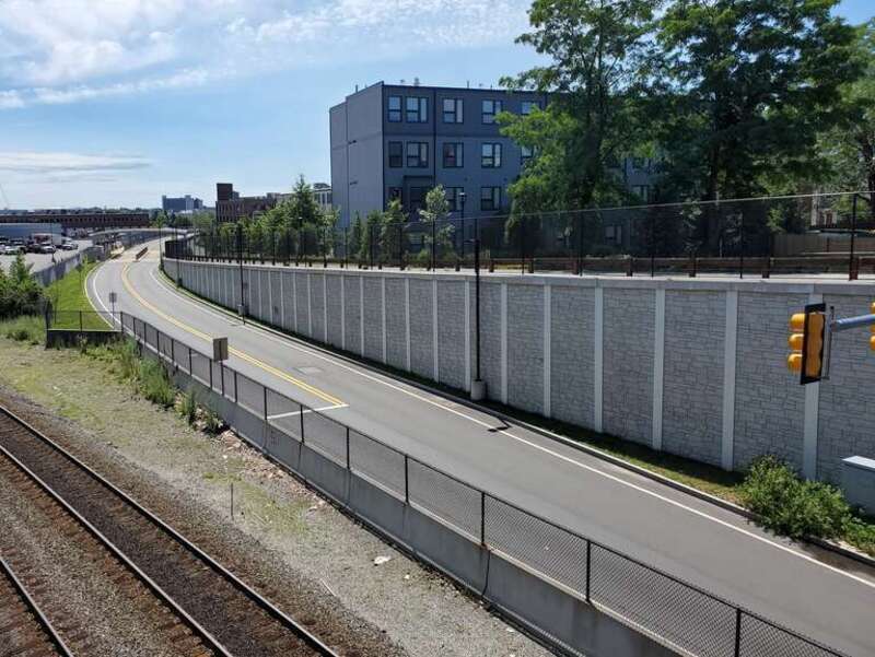 Silver Line busway viewed east from the Broadway bridge in July 2021. The busway narrows to a single lane to pass under the narrow bridge, with a traffic signal controlling the short one-lane segment.