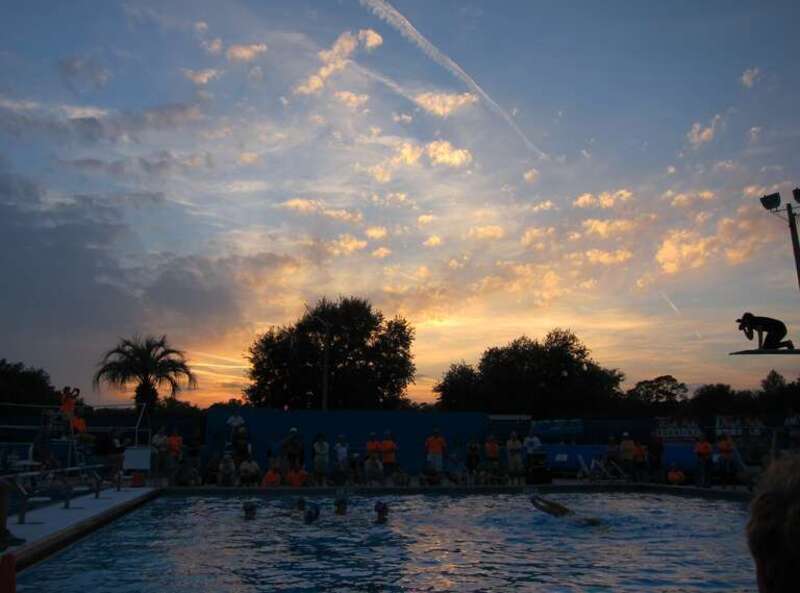 Sunset over synchronized swimmers, and photographer balanced on diving board