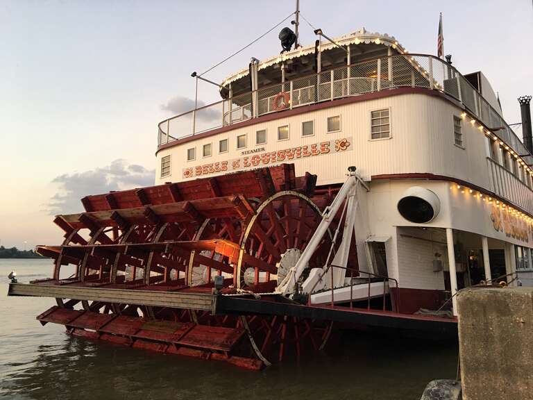 The Belle Louisville is docked on the Ohio River in Louisville, Kentucky, at sunset. This steamboat was first launched in 1914 in Pittsburgh, Pennsylvania. The boat has gone through several name changes, first being called the Idlewild and renamed