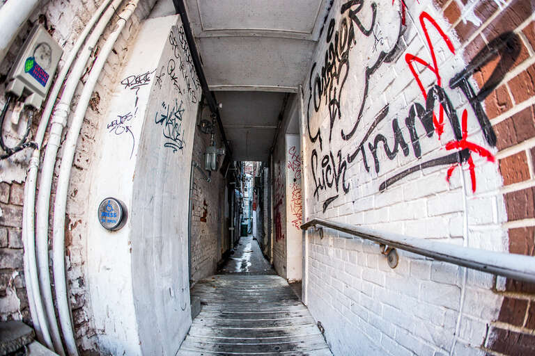 Some graffiti tagged on a wall in a narrow alley in Iowa City.