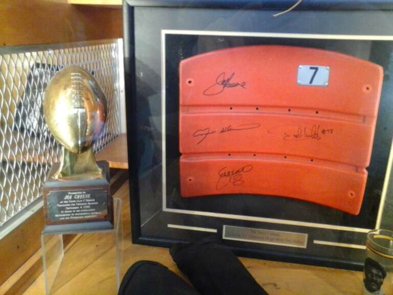 Closeup of Joe Greene's trophy and a Three Rivers Seat signed by the Steel Curtain in the Heinz Field Walk of Fame.