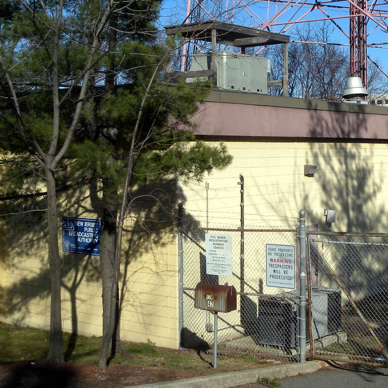 Looking east at signs on the fence of File:WNJN-TV Montclair dishes jeh.jpg on a sunny afternoon.