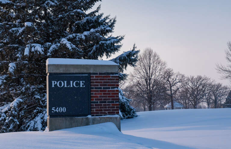 The entrance sign for the City of Brooklyn Park Police Department headquarters at 5400 85th Avenue North in Brooklyn Park, Minnesota, on a snowy afternoon.
