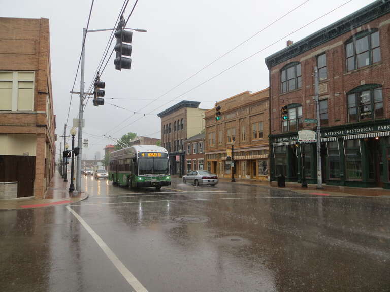 Greater Dayton RTA trolleybus 1404, a 2014-built Gillig/Kiepe dual-mode trolleybus, westbound on route 4, on Third Street at Williams Street, in a pouring rain.