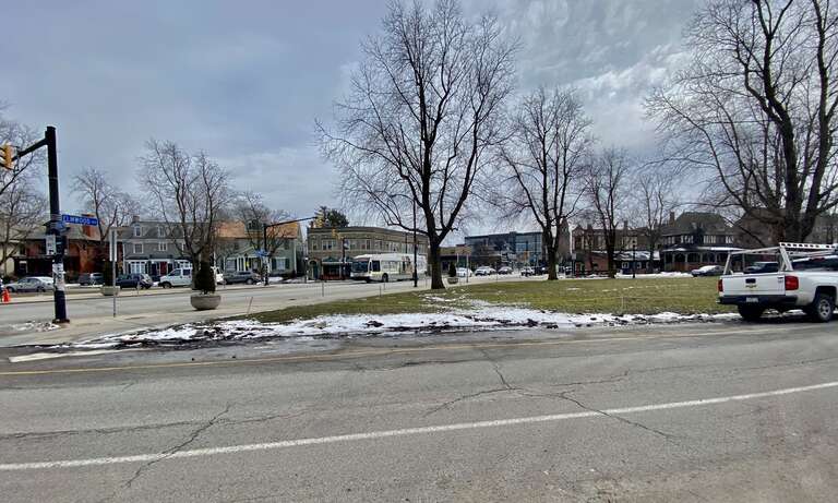 As seen in the historic Elmwood Village of Buffalo, New York on a March 2022 afternoon, an outbound NFTA Metro bus on route #20 crosses verdant Bidwell Parkway as it plies its prescribed northbound route along Elmwood Avenue. The bus will end its run