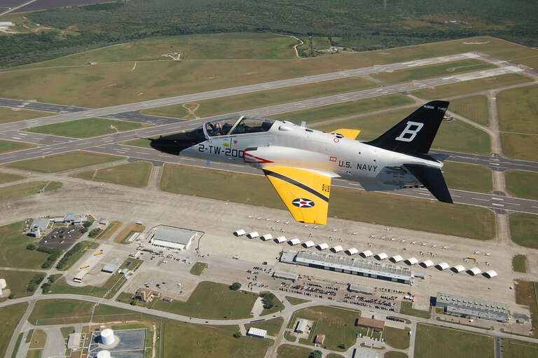 A T-45 Goshawk training aircraft painted in a pre-World War II tactical aircraft paint scheme flies over Naval Air Station Kingsville, Texas. The plane is one of nine training command aircraft being painted in celebration of the Centennial of Naval