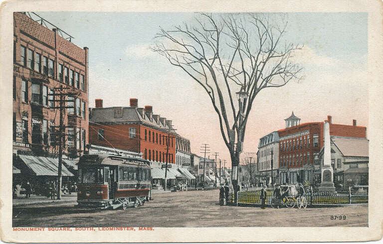White border postcard of a streetcar at Monument Square in Leominster, Massachusetts. The positioning of the streetcar indicates it is a Worcester Consolidated Street Railway car headed south. The rear of the postcard lists several streetcar