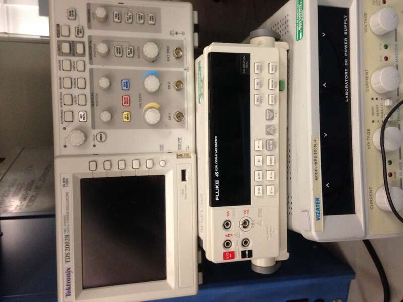 A stack of common electronic test equipment, specifically a Tektronix TDS 2002B Oscilloscope, a Fluke 45 Multimeter, and a Vizatek MPS-3005L-3