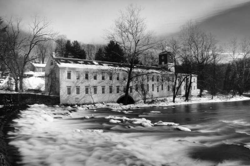Winter at Breck's Mill is a black and white landscape photograph of a winter scene on the Brandywine Creek in Wilmington, Delaware. The building shown is Walker's Mill, on the east side of the creek across from Breck's Mill.