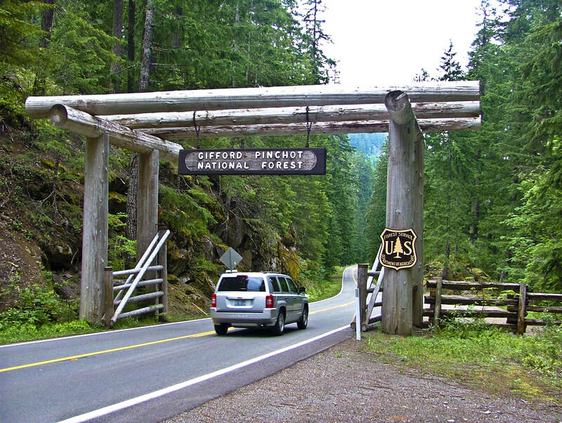 Vehicle driving through Nisqually Historic District Gate on the Gifford Pinchot National Forest and Mt Rainier National Park in Washington's Cascades by Longmire Washington.