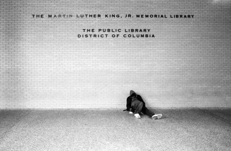 A man sitting against a wall at the Martin Luther King, Jr. Memorial Library located in the Penn Quarter neighborhood of Washington, D.C.
