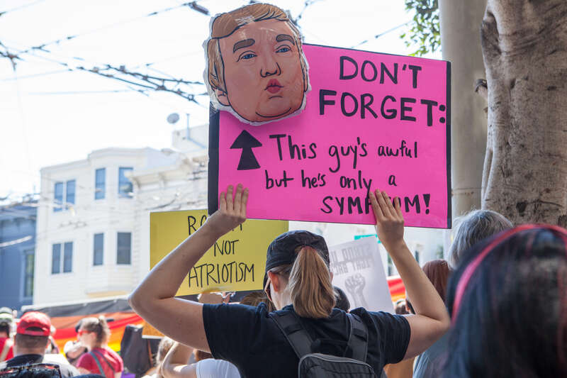 A protester holds a sign with a drawing a Donald Trump and the words "Don't Forget: This guy's awful but he's only a symptom!" at a Patriot Prayer counter-protest in San Francisco.