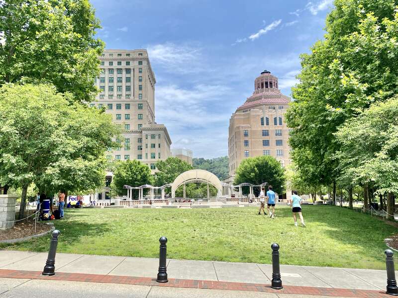 On the left, built in 1924-1928, this Classical Revival-style building was designed by Frank Pierce Milburn to serve as the Buncombe County Courthouse, replacing a previous courthouse that stood immediately in front of the present building, which was
