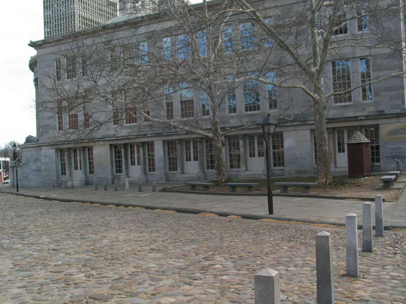 The northern side of the Merchants' Exchange Building in Philadelphia, Pennsylvania, USA. The road guarded by bollards is Dock Street. The camera is facing roughly southeast.