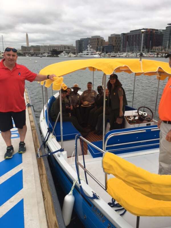 Rangers board a boat in the Washington Channel.
Park rangers in small boat with man on dock.