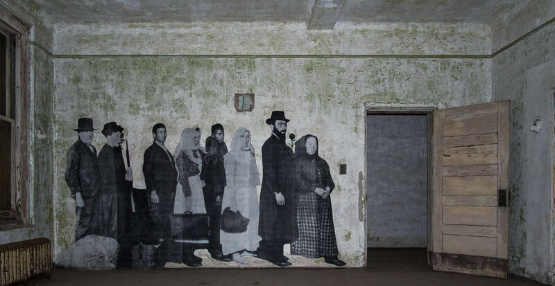 The Ellis Island Immigrant Hospital, closed since 1930. The photograph is one from the early 20th century, when the hospital was operational. In 2014 the French artist JR put up large reproductions of such photographs around the hospital grounds.