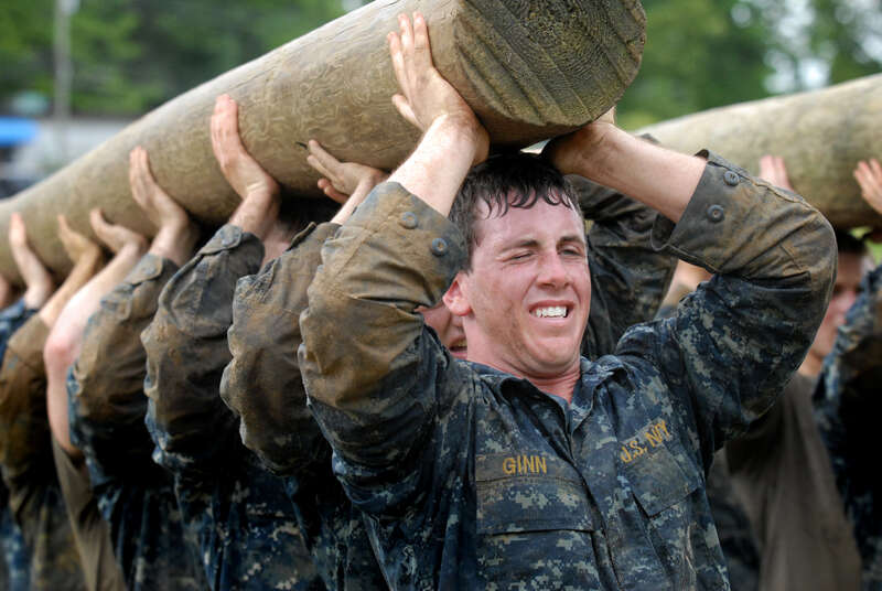 Plebes carry a modified telephone pole during the log PT station of Sea Trials, the capstone training exercise for Naval Academy freshmen. The plebes navigate physical and mental challenges, ranging from obstacle courses, long-distance group runs,