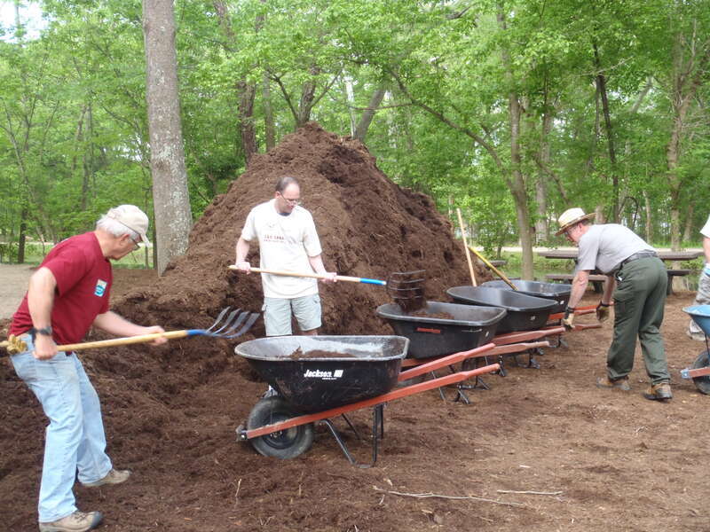 Park Superintendent Kevin Brandt works with volunteers spread mulch throughout the day use area and concession stand.