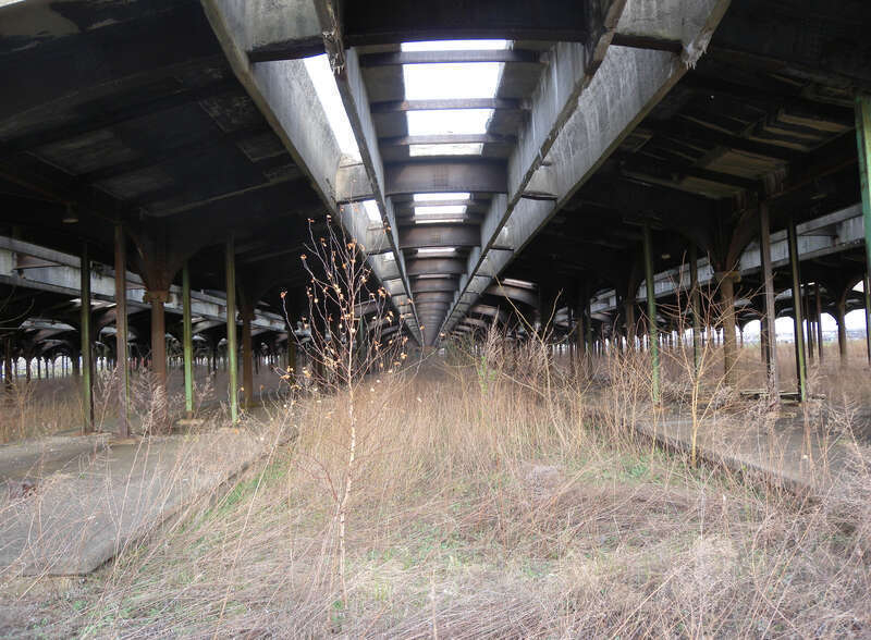 Looking east through western fence, into train shed on a mostly sunny afternoon.