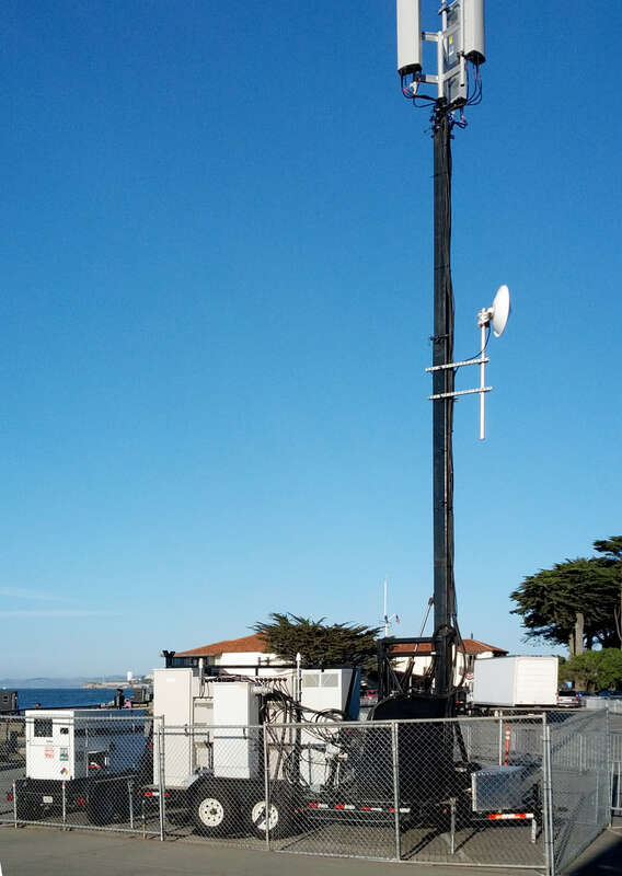 Verizon mobile cellular radio site trailer with antenna mast deployed and electrical generator trailer (to the left) for temporary augmented cell phone coverage.