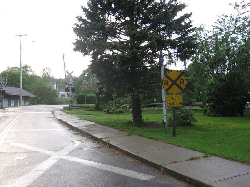 The School Street level crossing of the Northeast Corridor in West Mystic, Connecticut.  The former New York, Providence and Boston railroad station is partially visible on the left on other side side of the tracks.  Note the sign that warns that