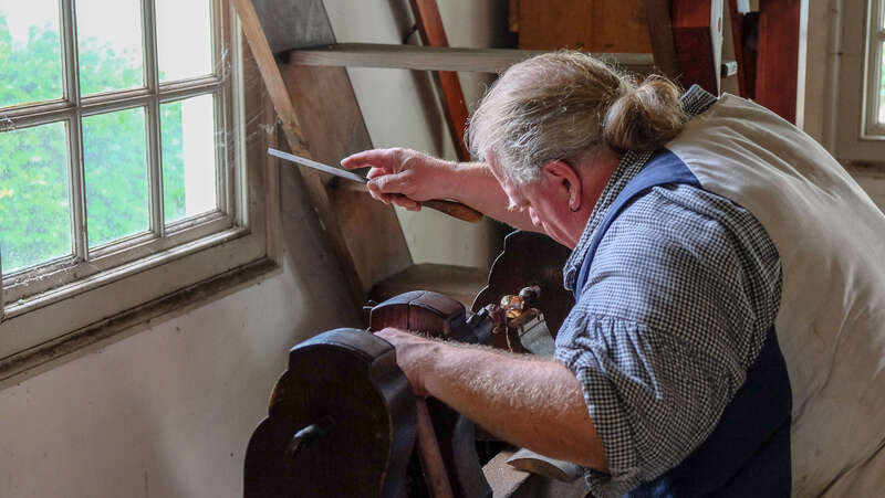 500px provided description: Man works on metal objects in Williamsburg. [#colonial ,#file ,#metal smih]