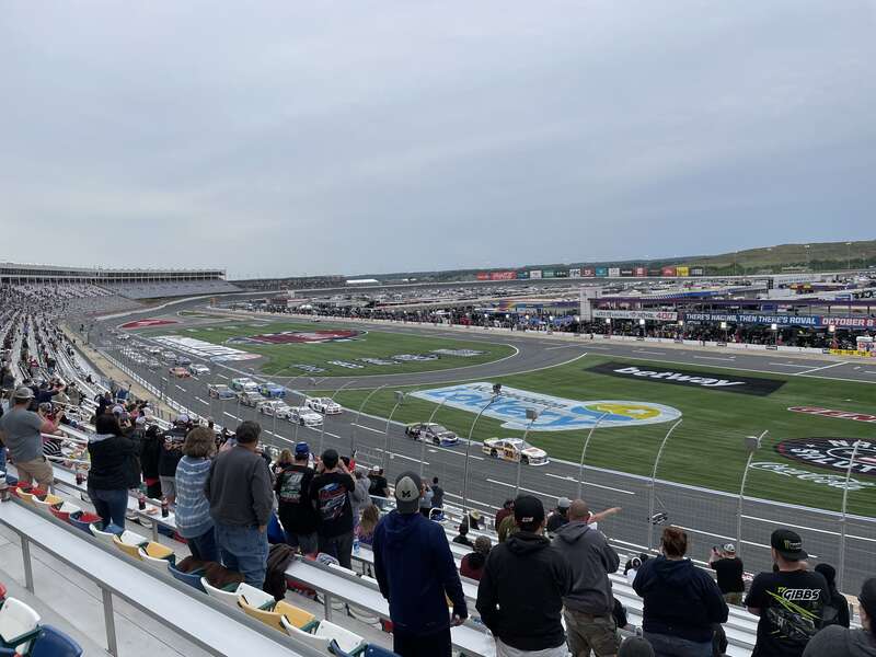 The 2023 General Tire 150 at Charlotte Motor Speedway viewed from the frontstretch. Jesse Love (#20) leads the field at the beginning of the race.