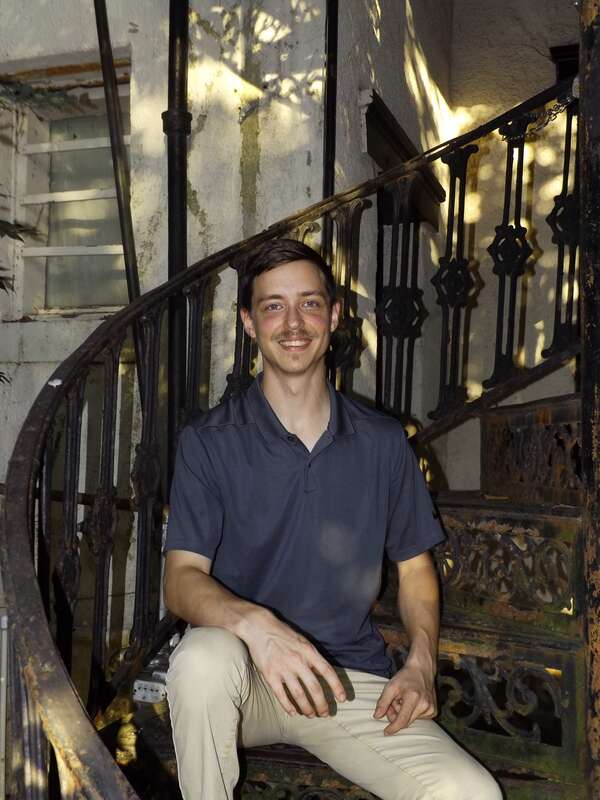Timothy Holdiness posing on a castiorn spiral staircase on Historic Front Street in Natchitoches, Louisiana.