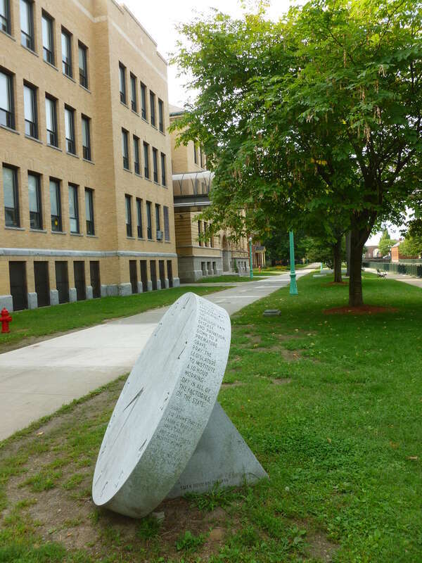 The right side of a 14 hour clock monument at Lucy Larcom Park, made by Ellen Rothenberg in 1996.  The work memorializes the &quot;10 hour movement&quot; of the early 1800's, spearheaded by female workers in Lowell.  
An inscription that circles along the