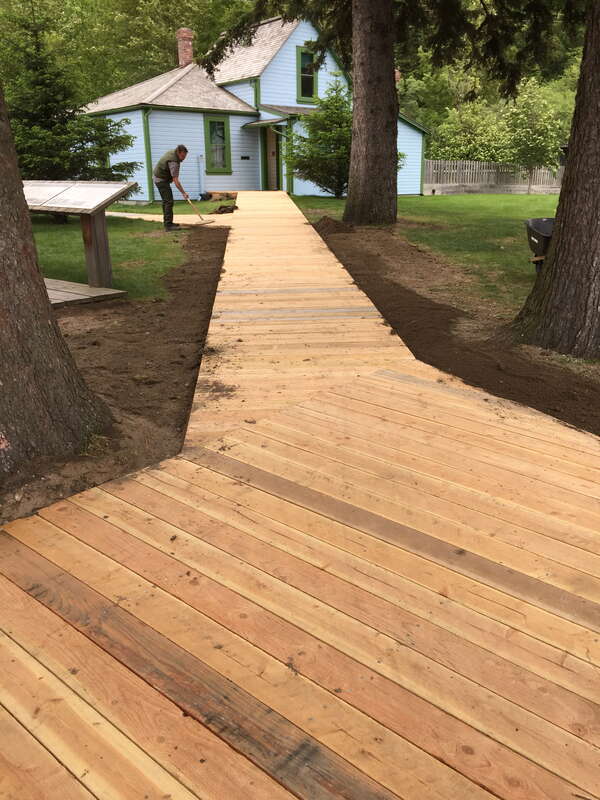 View of a park service employee working the grounds at Klondike Gold Rush National Historical park in summer along the accessible boardwalk to the Ben Moore House.
Ben Moore House boardwalk at Klondike Gold Rush National Historical Park after