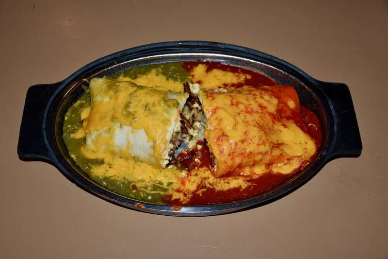 A New Mexican breakfast burrito from the Tia Sophia's diner in Santa Fe, served smothered (covered in chile sauce and melted cheese), Christmas-style (both red and green chile), containing scrambled eggs, bacon, and hash browns.