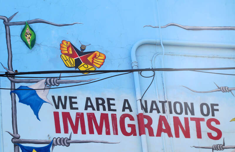 Words 'WE ARE A NATION OF IMMIGRANTS' from 'Declaration of Immigration' mural by Yollocalli Arts Reach, located at 1413 W 18th Street in Pilsen, Chicago, Illinois. Photographed in September 2014.