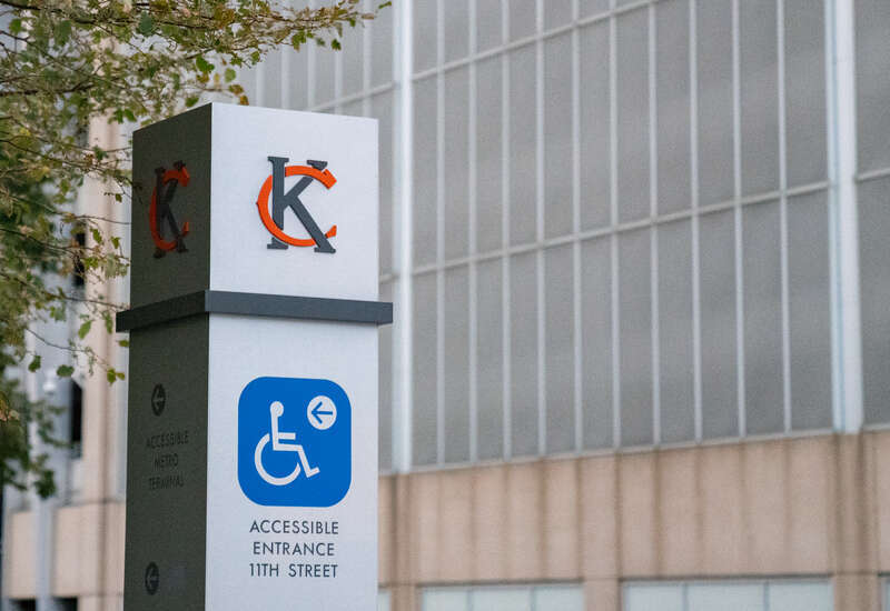 Signage at Kansas City City Hall, Missouri (KCMO) has a &quot;KC&quot; logo and accessible entrance information.
