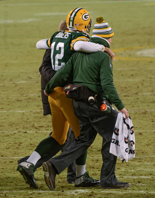 Aaron Rodgers being helped off the field after injuring his calf in a 2014 game against the Detroit Lions