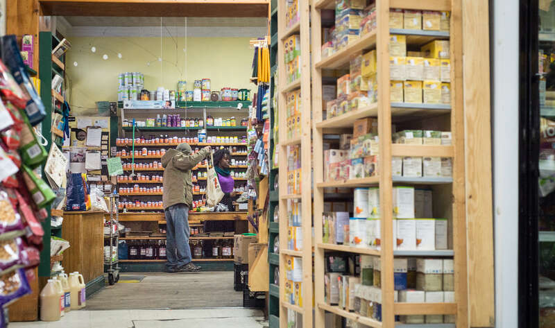 Glut collective member Shauntrice Martin  working the main register, welcomes and helps customers along with fellow worker-owners and volunteers, and take care of accounts payable to vendors at this worker-owner cooperative store, that serves the