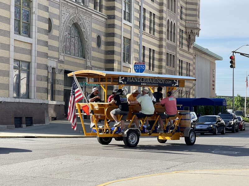 Party bike cruising through a red light at a busy intersection in Indianapolis, Indiana.