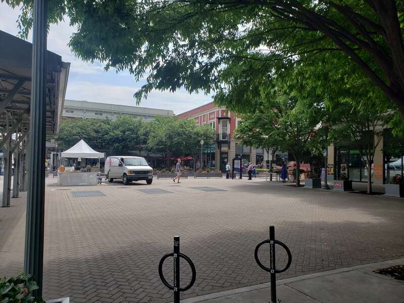 Corner view of the Roanoke Market Square. Shows a truck selling donuts, pedestrian mall and a tree in the foreground. Photo taken in May 2023.