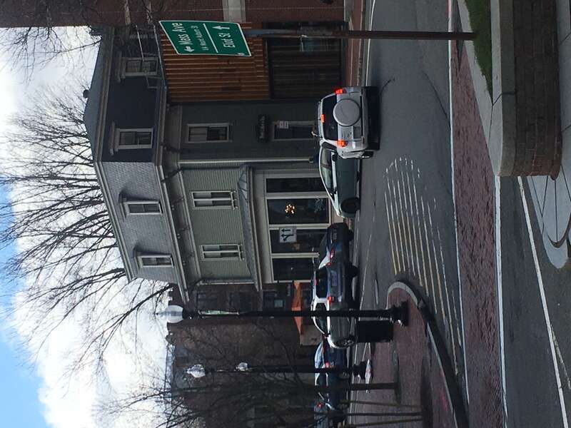 The original site of Elizabeth Glover's house in Cambridge, MA. A sign outside the building highlights the historical significance of the location.