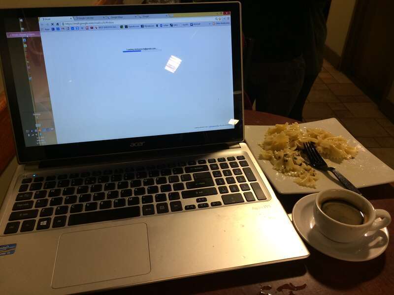 Laptop with food and drink at a cafe.